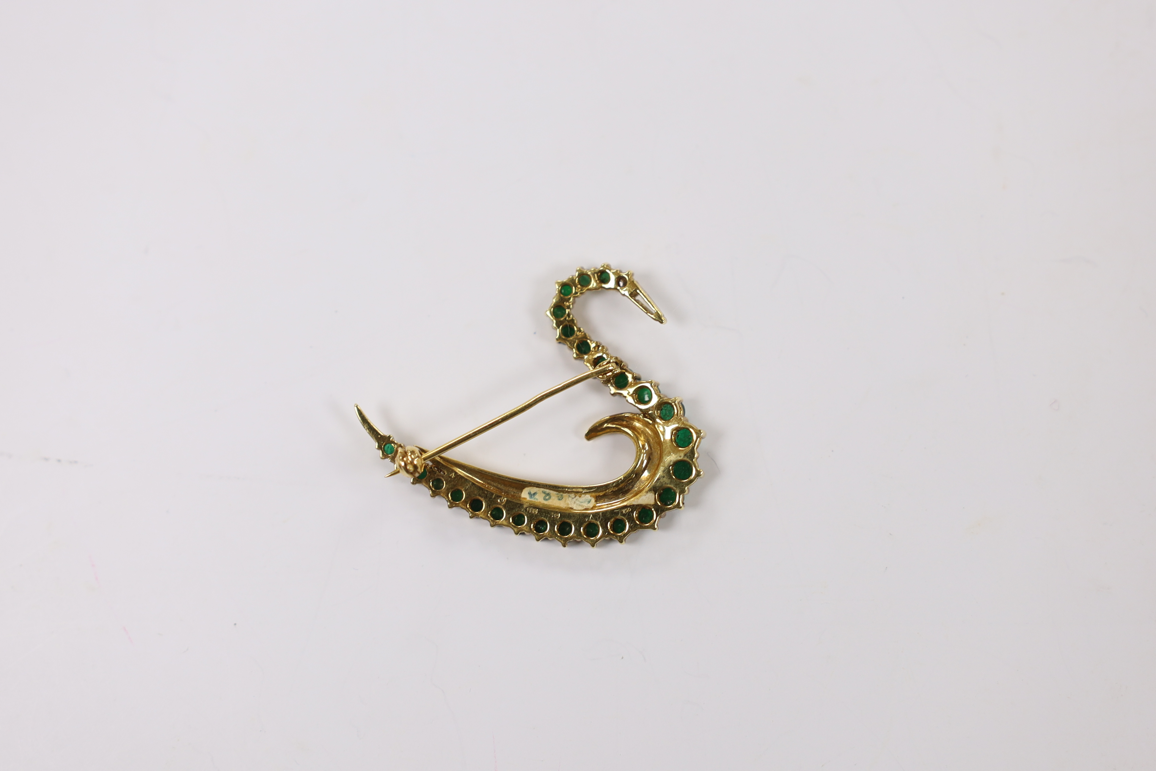 A late 1980's 18ct gold, emerald, and diamond cluster set brooch, modelled as a swan, with trapeze cut diamond set beak, maker's mark COLJ, height 34mm, width 41mm, gross weight 9.3 grams.